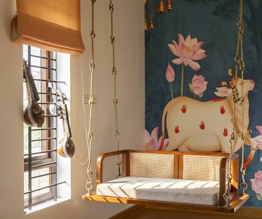 In the living room of our Banashankari residence, a traditional wooden swing becomes a playful centerpiece. This space embodies my approach of integrating nostalgic elements into a modern, light-filled home, using Jaisalmer stone flooring and a wood-and-cane false ceiling to create an earthy, grounded feel.