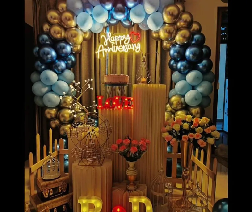 I designed this elegant anniversary decoration with a striking blue and gold balloon arch. The setup is personalized with the couple's initials in marquee letters and a romantic "Happy Anniversary" neon sign, creating a perfect photo backdrop for their special day.
