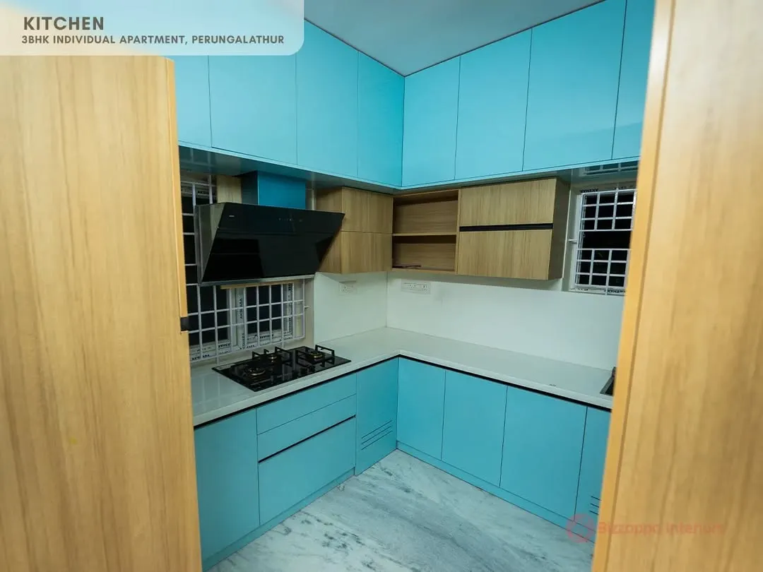 We love playing with color to bring personality into your home. This L-shaped modular kitchen features a refreshing dual-tone combination of vibrant blue and warm wood, finished with high-gloss laminates for a sleek, contemporary look.