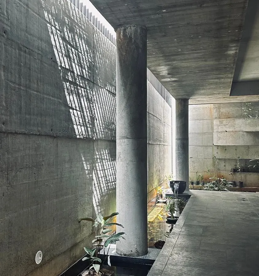 An exploration of light and shadow within a concrete passage. We believe architecture is an experience, and here we use natural light filtering through a skylit corridor to create dramatic, shifting patterns along a tranquil water feature.