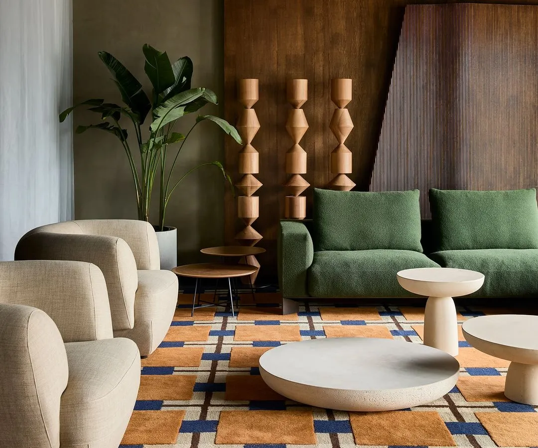 A living room vignette from the Ventura furniture gallery in Hyderabad. I designed the store as a series of 'mini homes' to help customers visualize the pieces in a real setting. This scene combines organic modern furniture, a bold geometric rug, and layered wood wall panels to create a warm, sophisticated atmosphere.