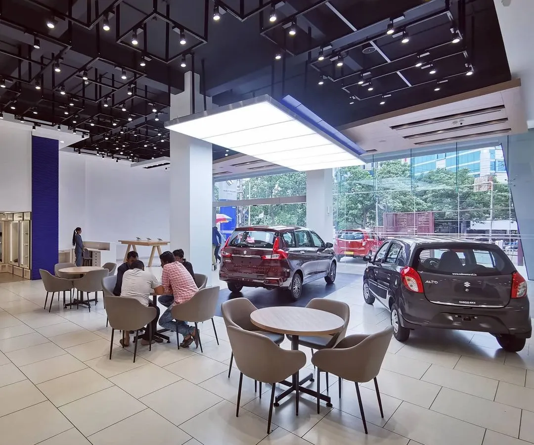 A view of the spacious and modern interior of a redesigned Maruti Suzuki Arena showroom. We focused on creating an open, welcoming environment with clear sightlines to the cars, comfortable customer seating areas, and dynamic ceiling and lighting design to enhance the retail experience.
