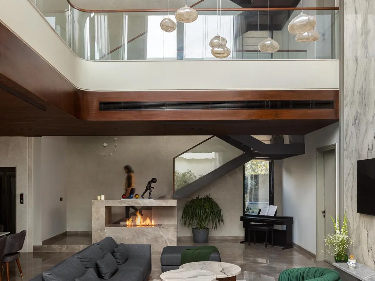 We believe in creating spaces that breathe. This double-height living room, anchored by a modern marble fireplace and cascading pendant lights, is the heart of the home. It’s a testament to our love for grand volumes, natural light, and creating a perfect balance between impressive scale and intimate comfort.