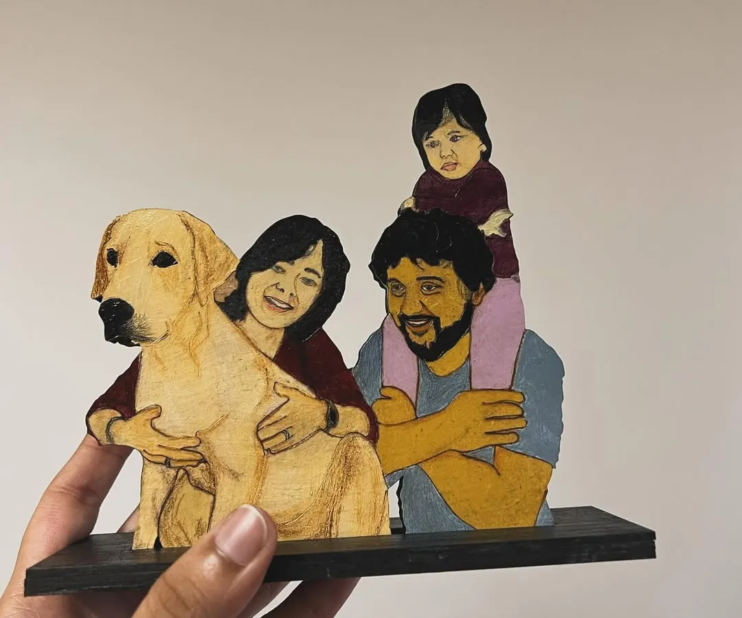 Your family, including your furry friends, can be turned into a beautiful wooden miniature. This custom illustration captures a precious family moment with their daughter and beloved dog, creating a perfect keepsake for a desk or shelf.