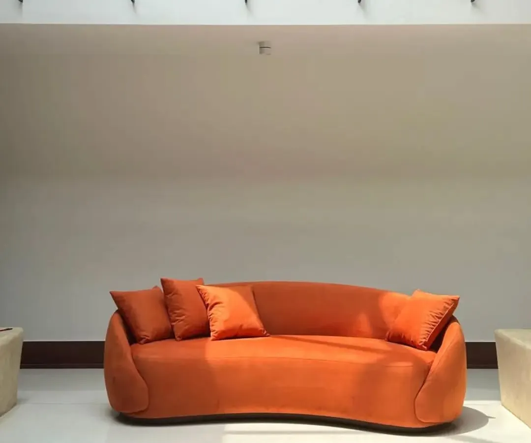 We love a bold color moment. This custom-curved sofa in a vibrant orange isn't just a piece of furniture; it's a statement. We work with you to pick fabrics and shapes that match your personality.