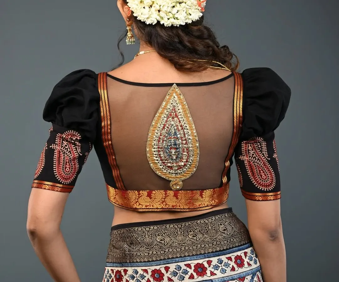 I love combining traditional elements with modern silhouettes. This black blouse features a sheer net back with an intricate, embroidered paisley motif, creating a look that is both elegant and alluring. The puffed sleeves add a touch of drama, making it a perfect choice for weddings and festive events.