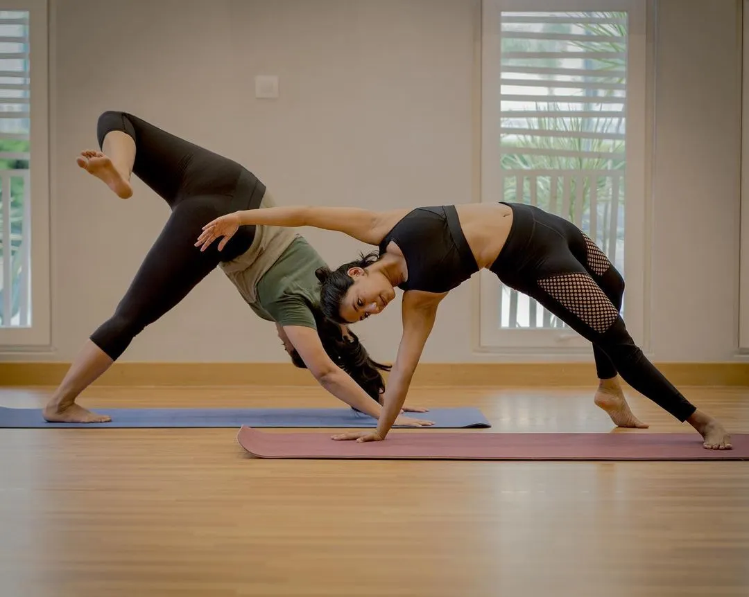 This is Camatkarasana, the Wild Thing pose, shared with a fellow yogi. In my group classes, we flow together, support each other, and create a space to explore poses like this heart opener. It’s a beautiful expression of shared energy and joyful movement.
