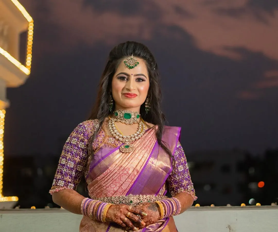 For my sister Sushma's reception, we went for a glamorous and sophisticated look. I created a soft glam eye with a hint of shimmer and a bold lip, paired with a modern half-up hairstyle with loose waves. This style perfectly complemented her elegant purple and gold saree and the evening's celebratory atmosphere.