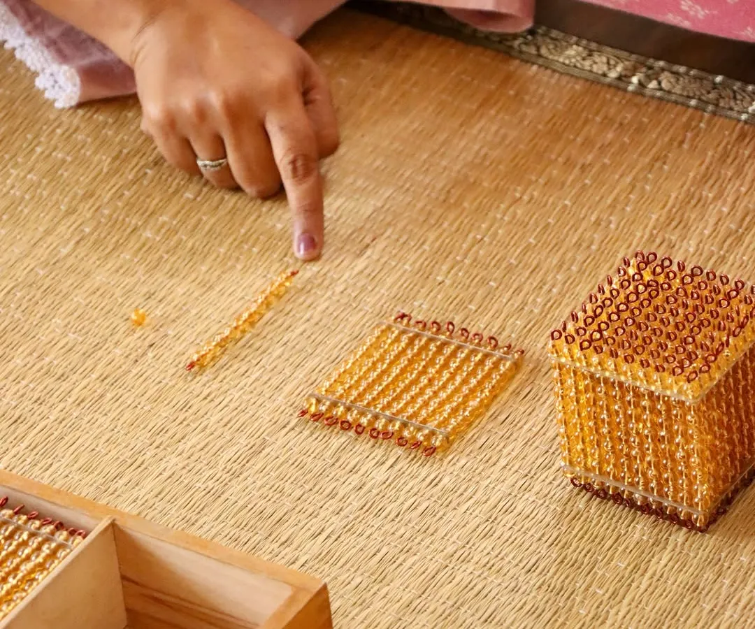 A single golden bead holds a universe of understanding. This is the heart of our philosophy: guiding the adult to see how simple, beautiful materials can open a child's mind to complex concepts like the decimal system. Learning with us is a process of joyful, hands-on discovery.