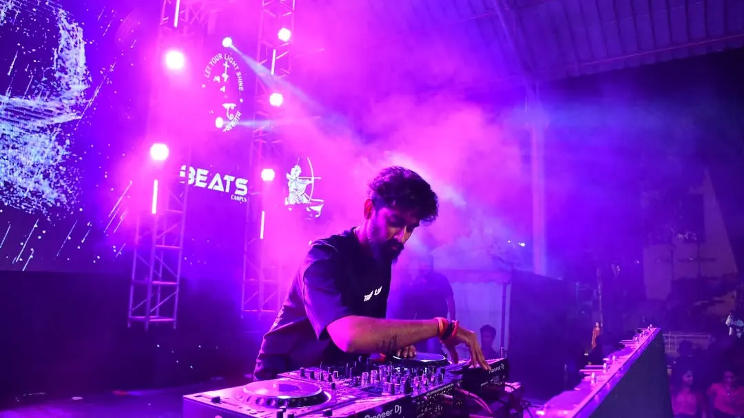 In the zone, mixing tracks on my Pioneer deck under the vibrant purple lights of a packed club. This is where I craft the perfect set, blending beats to keep the dance floor on fire all night.