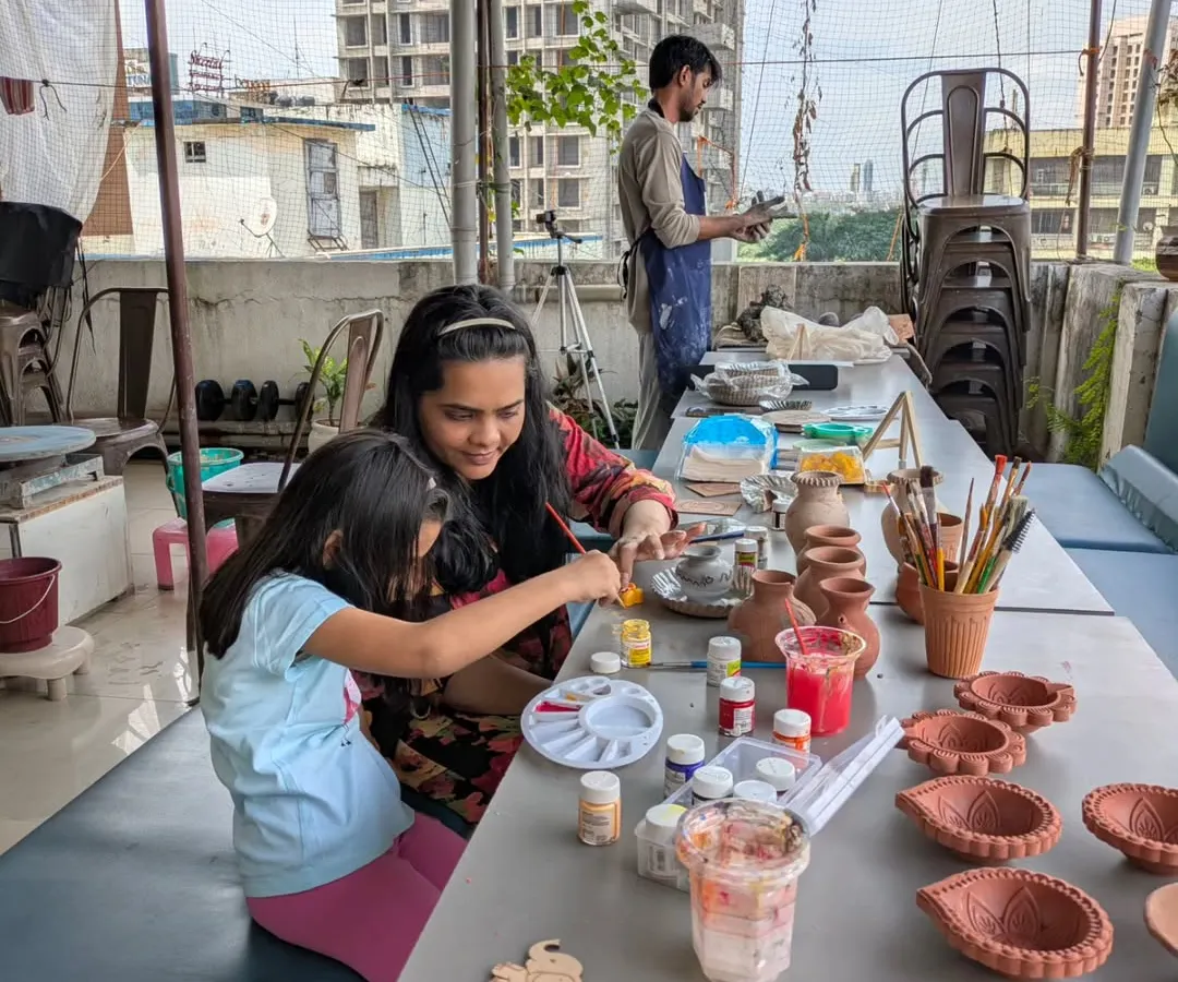 Pottery is a perfect family activity. Here, a mother and daughter are spending quality time together, painting their handmade creations at my open-air studio in Malad.