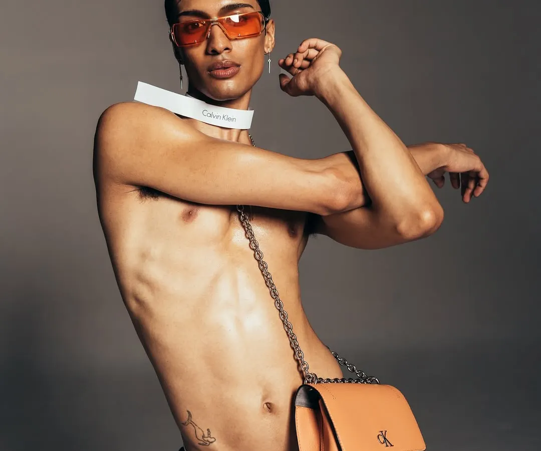 A dynamic shot for a Calvin Klein campaign, highlighting the brand's modern aesthetic. The composition uses strong lines and a confident pose to create an edgy, commercial photograph.