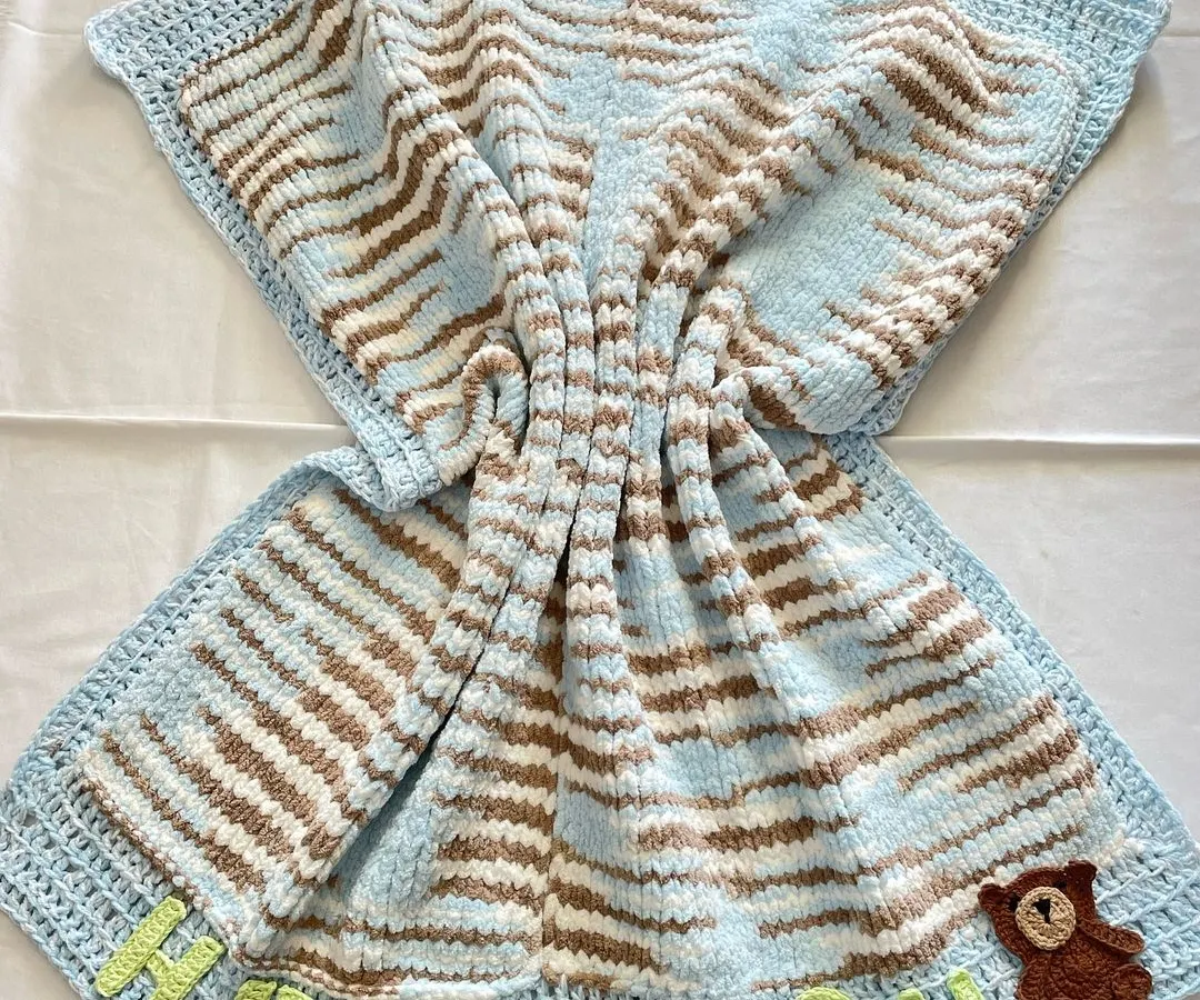 This is our premium "Cuddle Blanket," and it's as soft as it looks. Unlike our other blankets, this one is knitted to create an extra plush and heavy feel. We personalized this one with the baby's name, "Hitaansh," and a small teddy bear appliqué, making it a truly unique newborn gift.