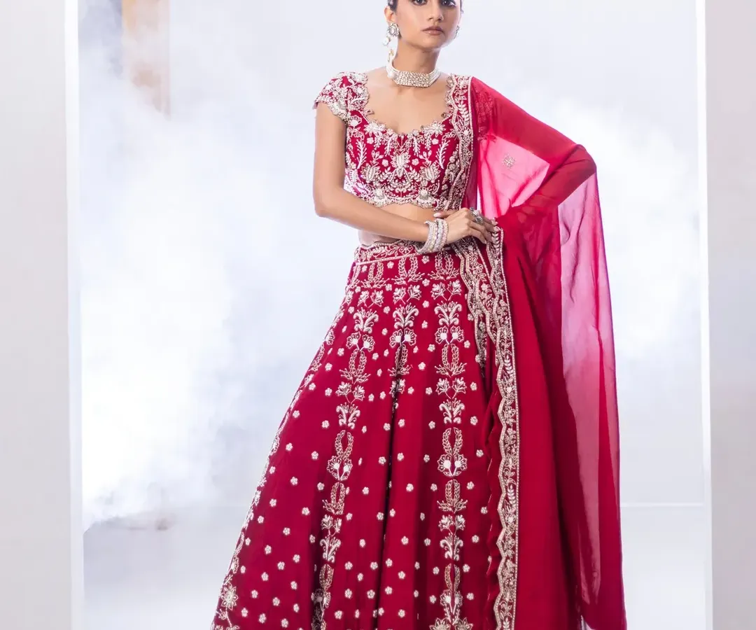 For the bride who loves tradition with a touch of modern grace, I present this reimagined red lehenga. The intricate contrast embroidery and classic A-line silhouette offer a timeless look, while the thoughtful detailing ensures it feels fresh and personal for your most important day.