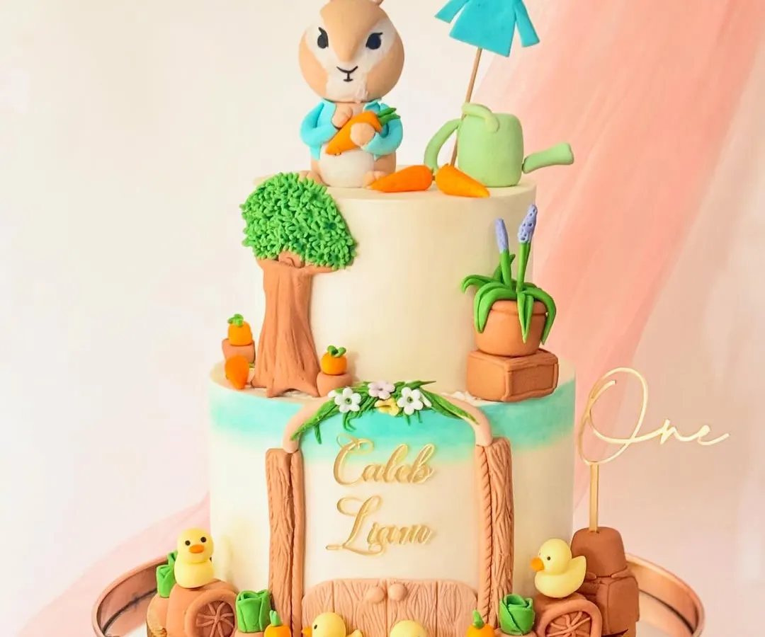 I brought the world of Peter Rabbit to life with this two-tiered buttercream cake. It features a hand-sculpted Peter Rabbit figure, a garden scene with tiny carrots and ducklings, and a personalized nameplate, making it a magical centerpiece for a first birthday.