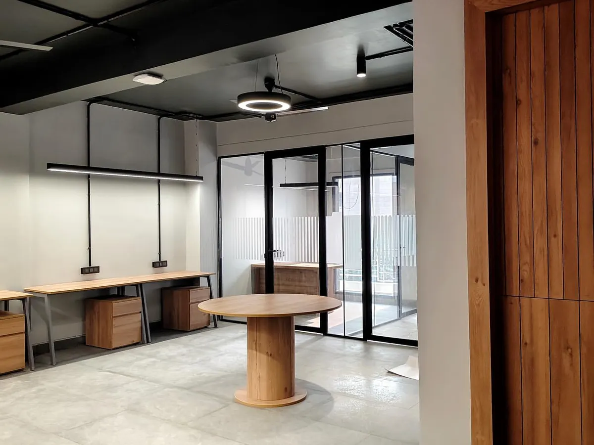 This open-plan office highlights our industrial-chic aesthetic, featuring an exposed ceiling, polished concrete floors, and sleek linear lighting. The layout is intentionally designed to foster collaboration while maintaining a clean, modern, and spacious feel.