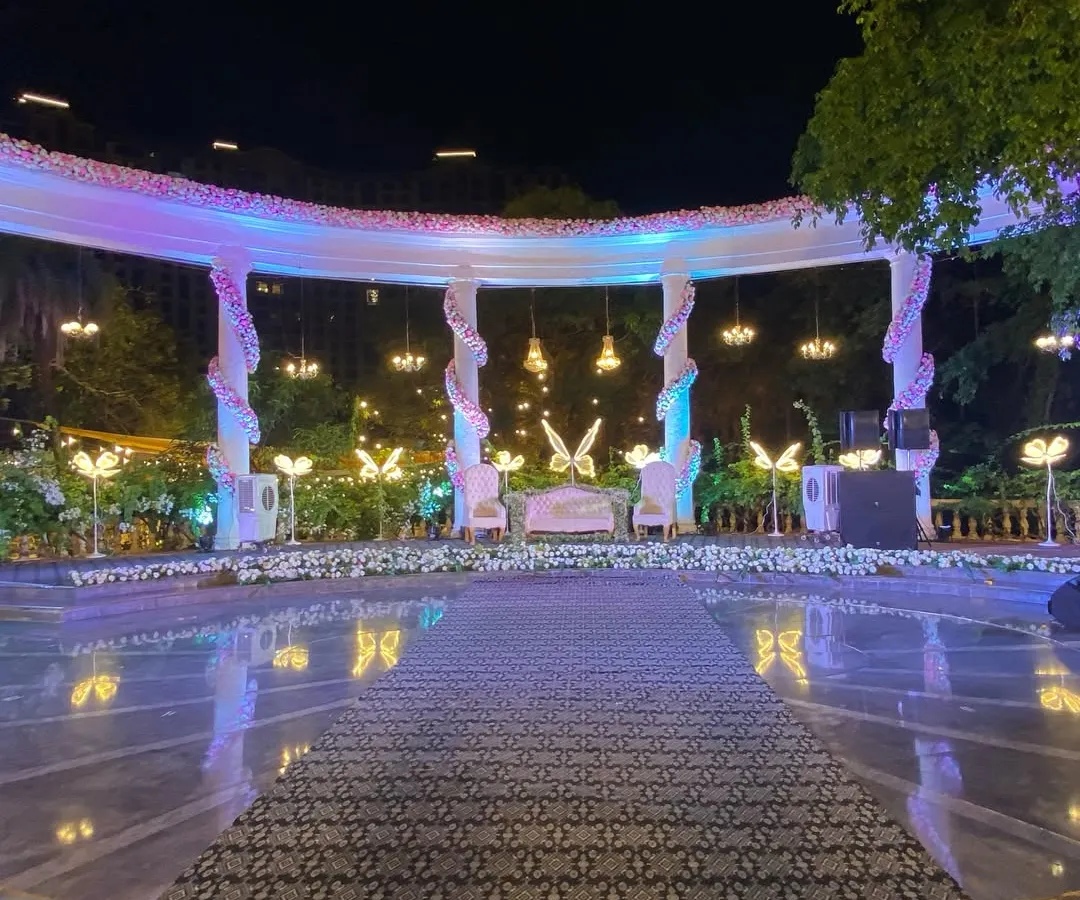 This elegant reception stage, set by a poolside, features a grand white structure with hanging chandeliers and glowing butterfly motifs. We designed it to be a magical focal point for the couple's special evening.