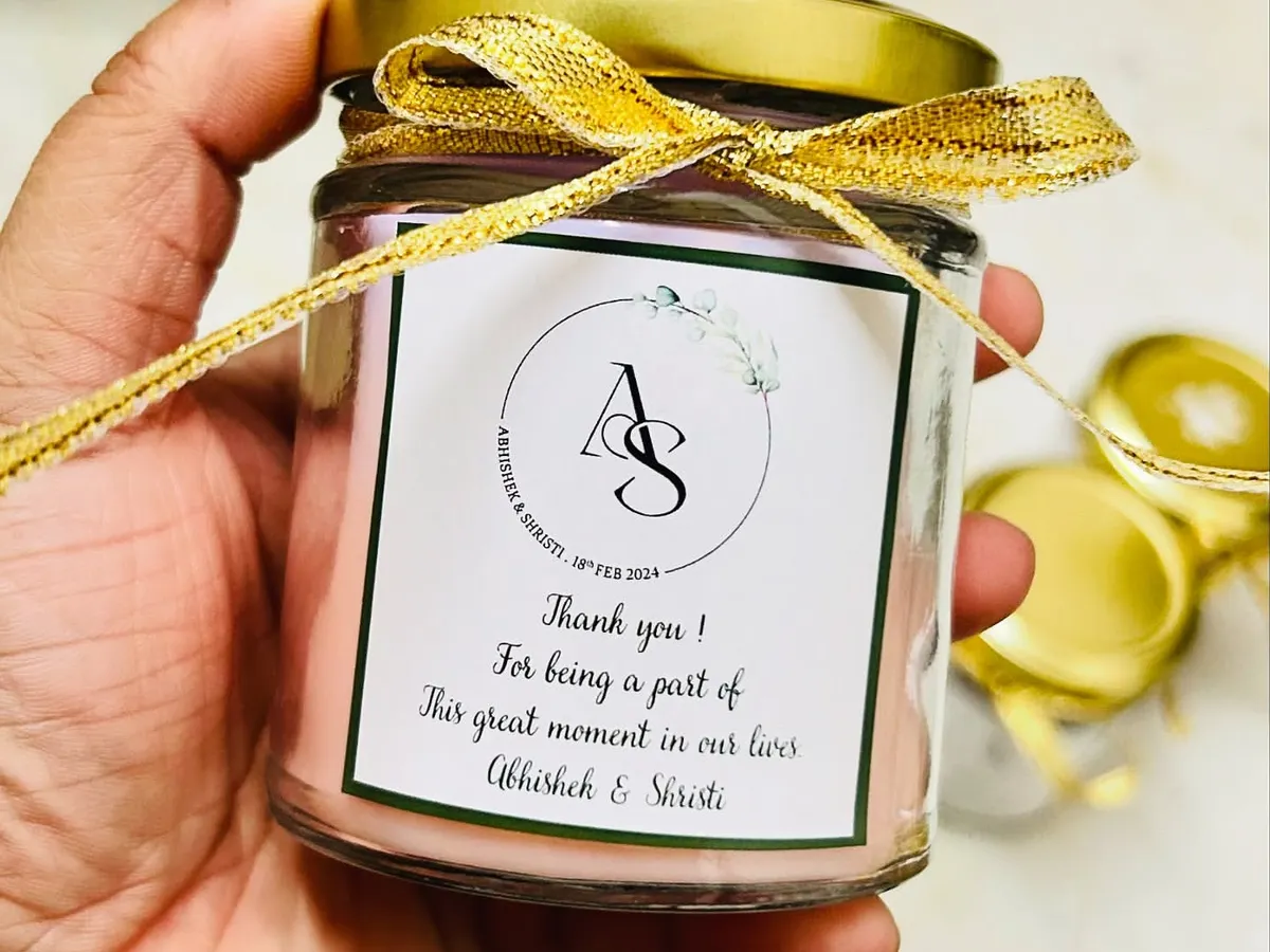 We love making your wedding favors feel personal. This is a close-up of a scented soy candle we customized with the couple's initials and a thank you message, finished with a delicate golden ribbon.