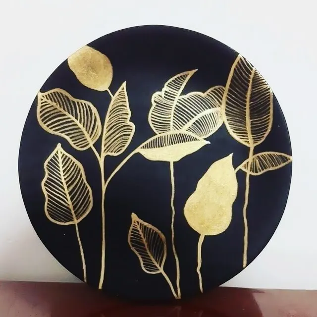 A modern take on botanical art, created with shimmering gold leaf on a dark circular canvas. I love how the simple, elegant leaf designs catch the light, making it a unique piece of home decor.