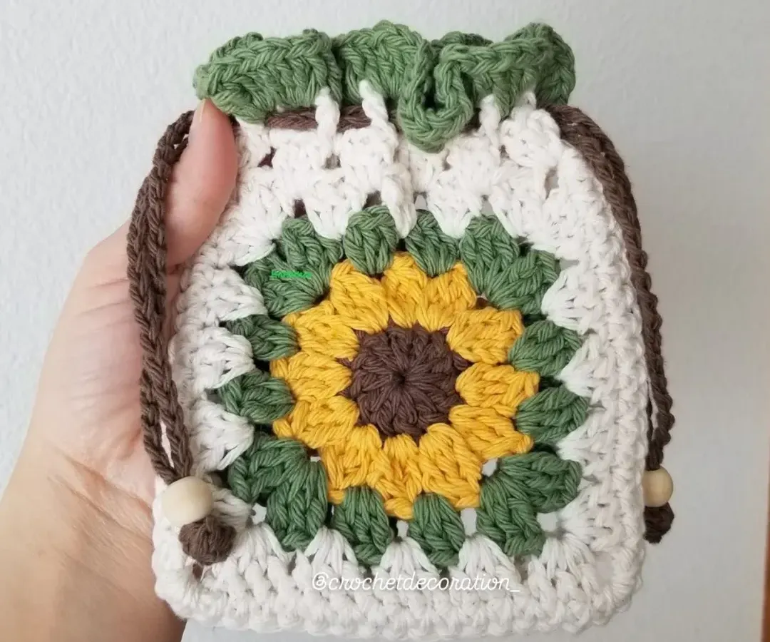 Our popular crochet sunflower pouch, designed with a classic granny square pattern. This drawstring bag is perfect for storing small treasures like coins, jewelry, or earphones, and is handmade with soft, washable yarn.