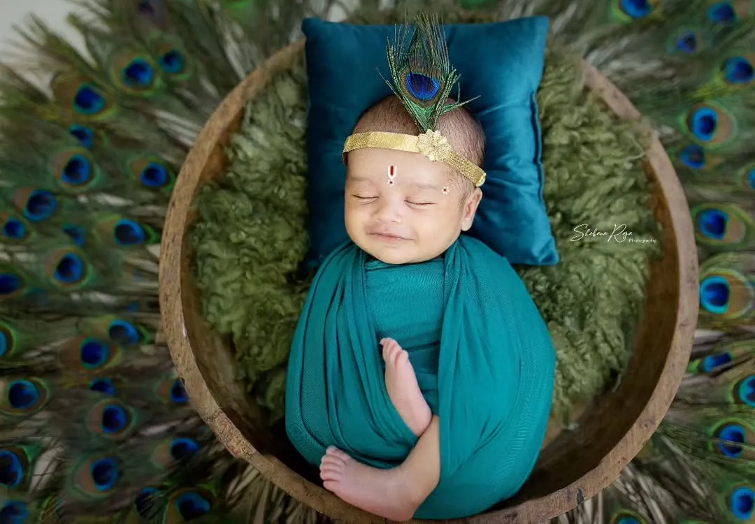 For my littlest clients, I offer unique traditional themes like this adorable Kaanha setup. This newborn photoshoot features a peacock feather headpiece and a serene, sleepy pose.