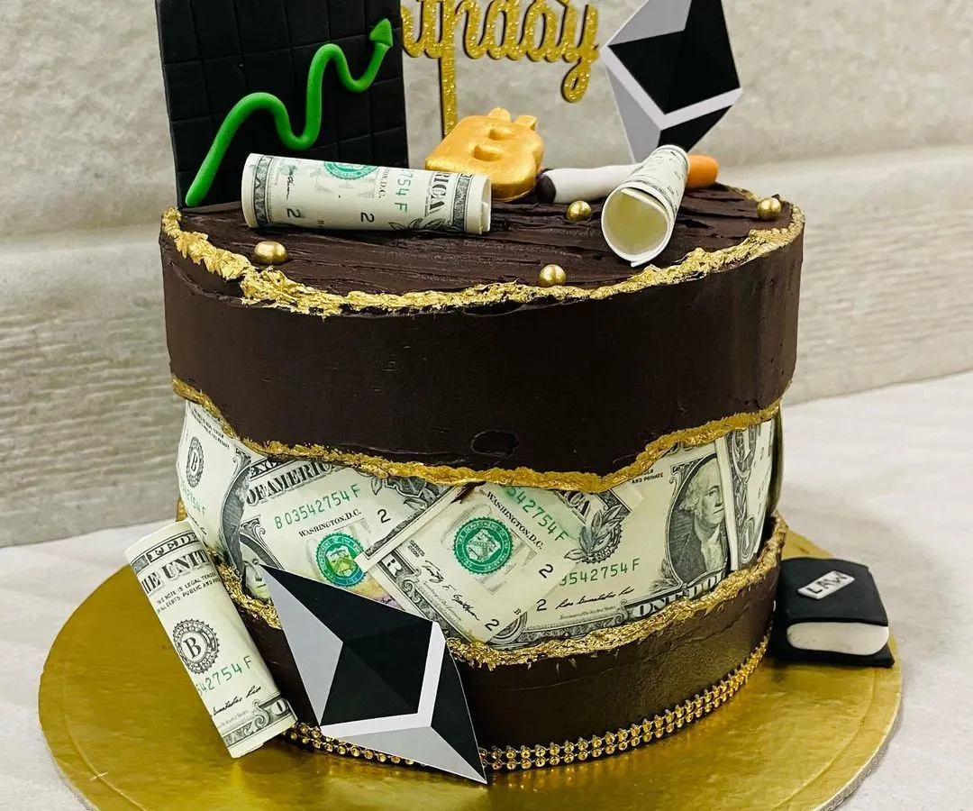 Your passions, baked into a cake. This custom two-tier design was for a crypto enthusiast, featuring edible money, Ethereum symbols, and a Bitcoin topper on a rich chocolate cake.