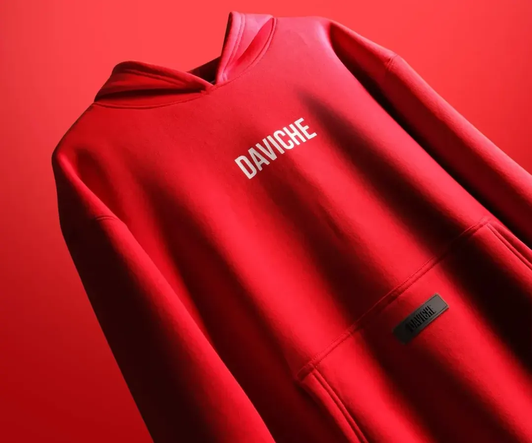 This vibrant red hoodie for the brand DAVICHE is captured with bold, directional lighting to emphasize the fabric's quality and the clean logo design. This style of apparel photography is perfect for brand lookbooks and hero website images.