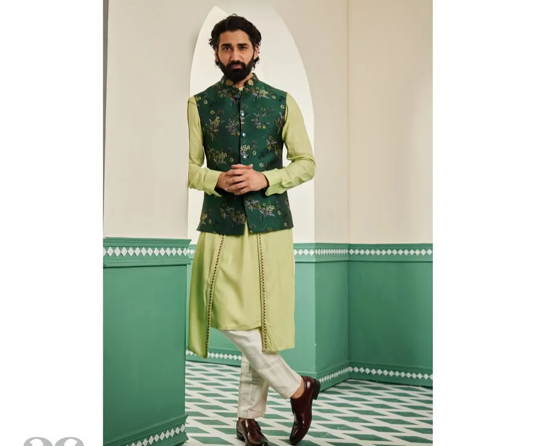 For festive occasions like a mehendi or sangeet, we design layered ensembles that are both elegant and comfortable. This look features a light green drape kurta paired with a contrasting emerald Nehru jacket, which is covered in our exquisite floral hand-embroidery.