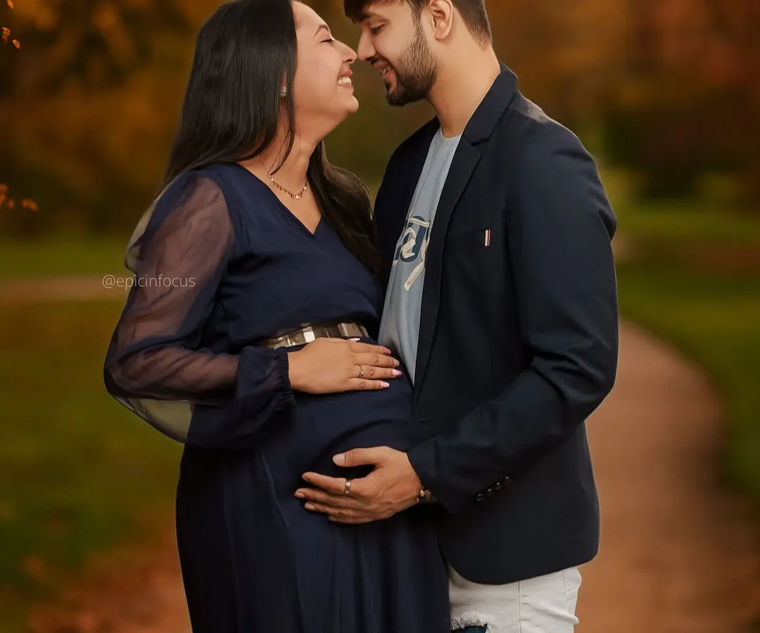 Capturing the shared joy and anticipation between partners. This outdoor couple's maternity portrait uses the warm tones of an autumn park to highlight the couple's close bond and excitement for their new arrival.