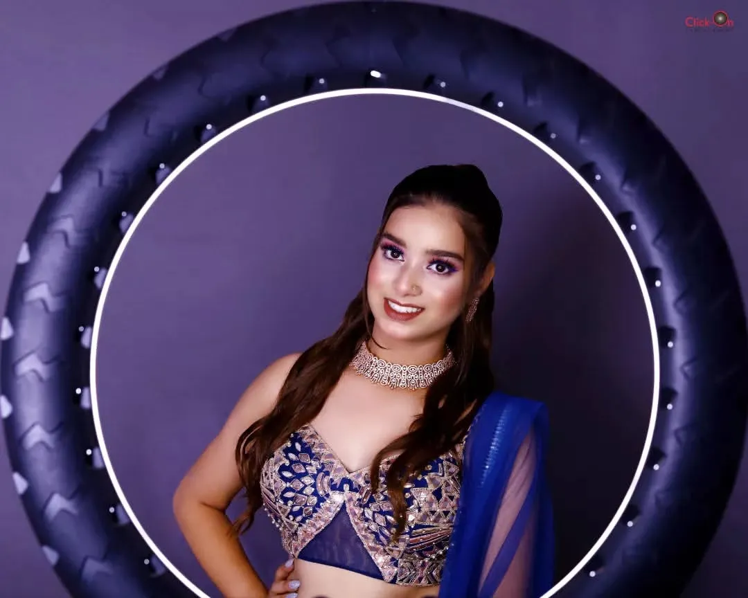 A modern studio portrait showcasing our use of professional lighting. The model, framed by a ring light, is wearing an intricate blue lehenga, highlighting our ability to create crisp, contemporary beauty shots for model portfolios.