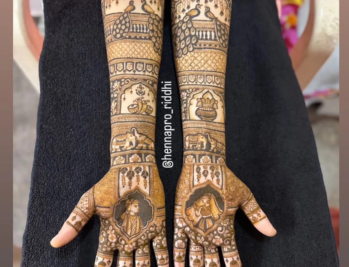 I adore creating full bridal arms with traditional Indian motifs. This design features majestic peacocks, auspicious wedding symbols like the kalash, and portraits of the bride and groom for a classic look.