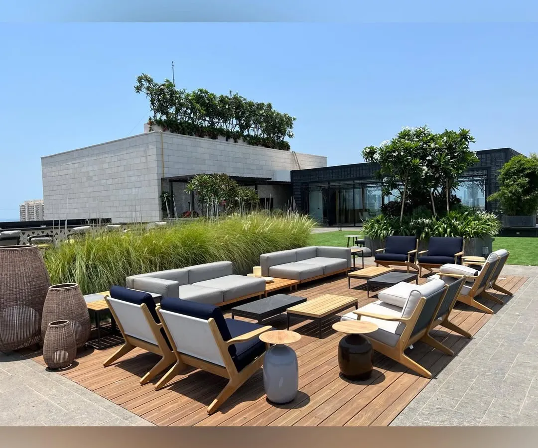 This rooftop lounge in Mumbai was designed as a luxurious escape with panoramic city views. The space features a custom wooden deck, comfortable outdoor sofas, and carefully selected ornamental grasses, creating a perfect setting for relaxation and social gatherings.