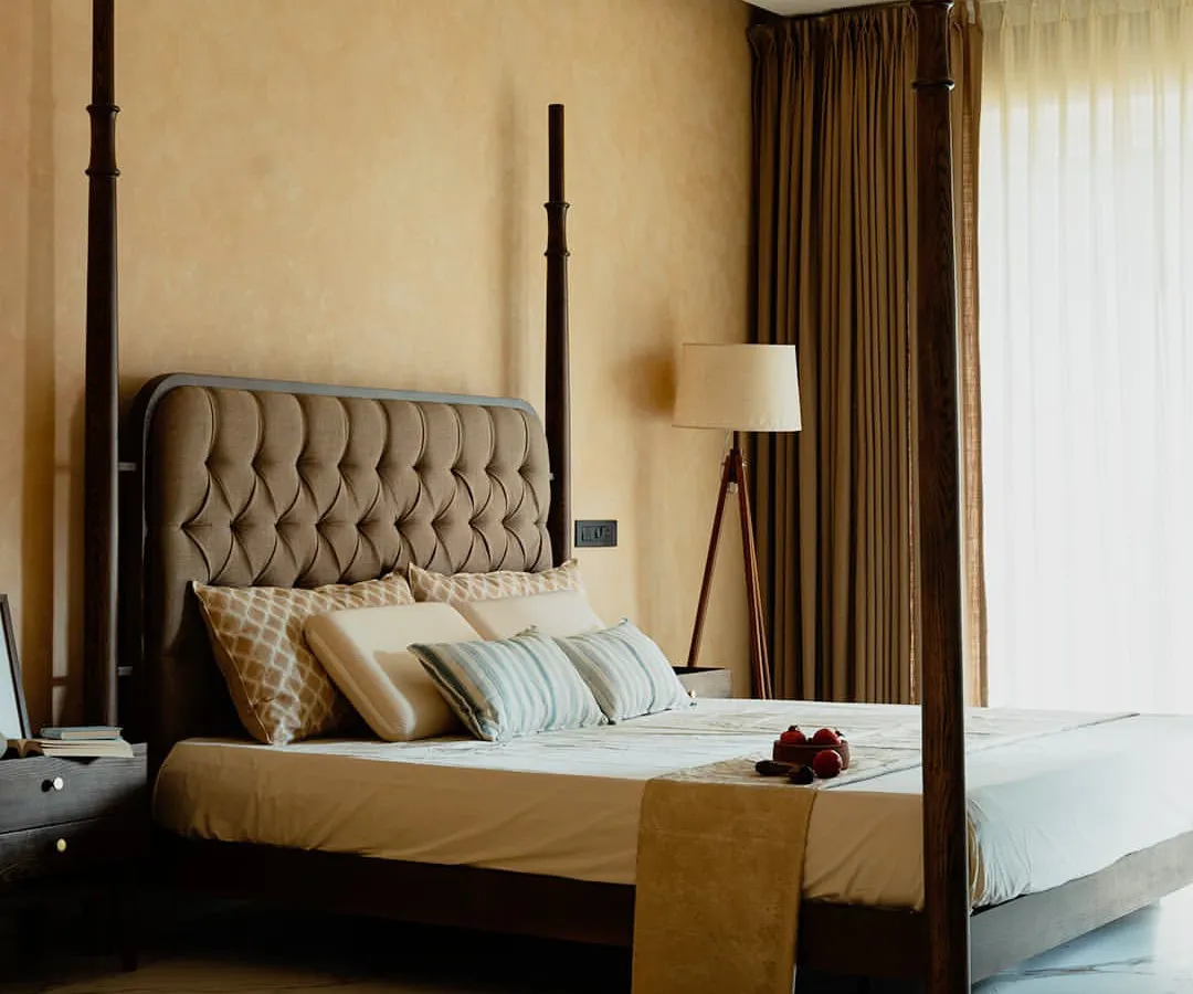 A masterpiece of bedroom design, this four-poster bed is handcrafted from solid teak wood. The tufted headboard adds a touch of classic luxury, while the warm, textured walls and ambient lighting create an intimate and serene sanctuary.