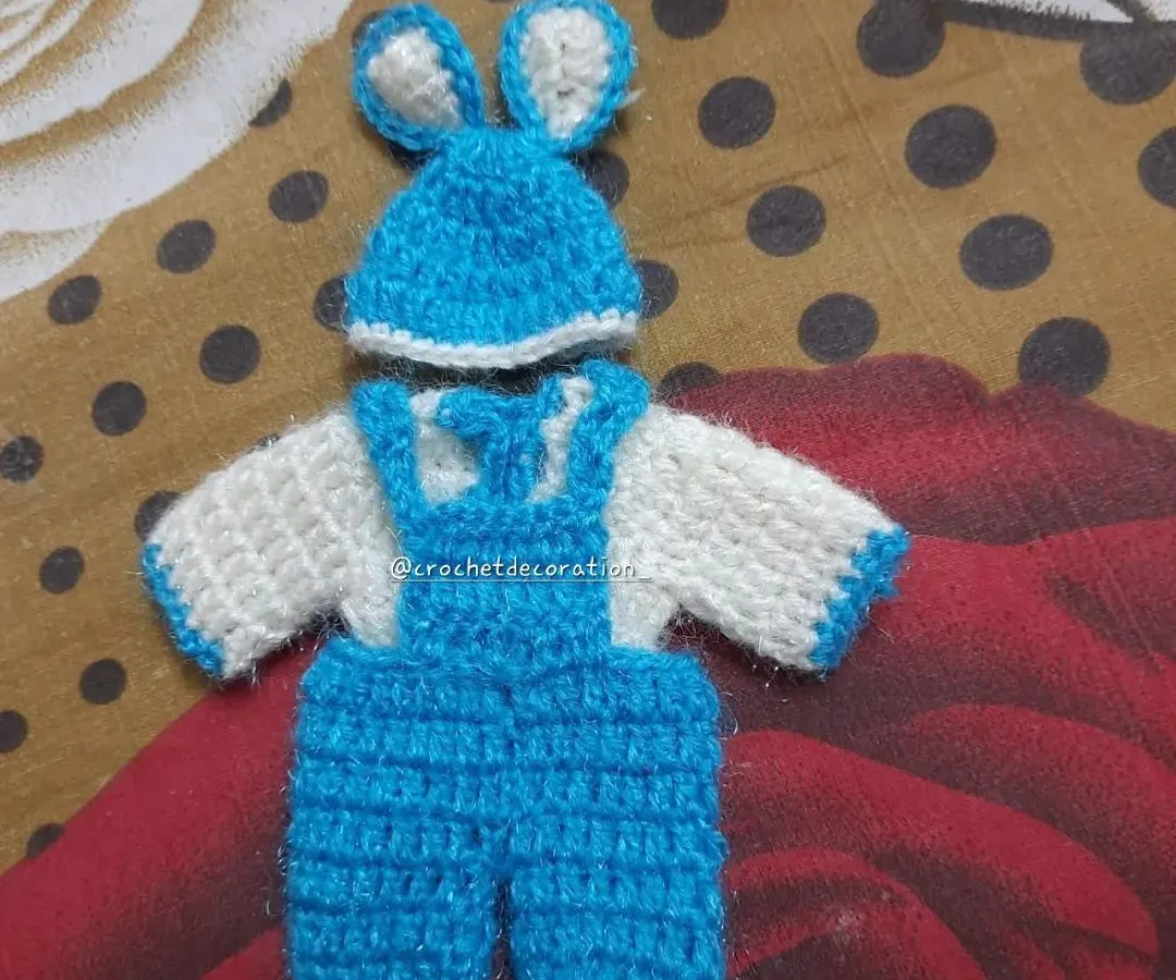 This playful crochet jumpsuit for Laddu Gopal features a white top with blue overalls and an adorable matching cap with bunny ears. It's a unique and modern outfit for your idol.