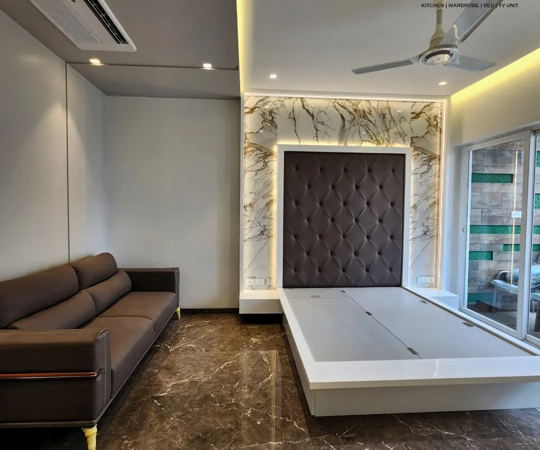 Here, a classic diamond-tufted headboard in dark fabric is framed by a stunning marble-effect feature wall with warm backlighting. The sleek, low-profile bed frame is designed with a lift-up mechanism for convenient under-bed storage.