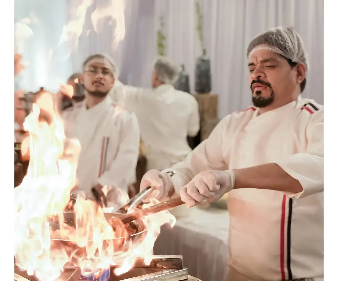 One of our chefs flambéing a dish at a live cooking station. This interactive culinary theatre is a highlight at many of our catered events, adding excitement and fresh flavors for your guests.