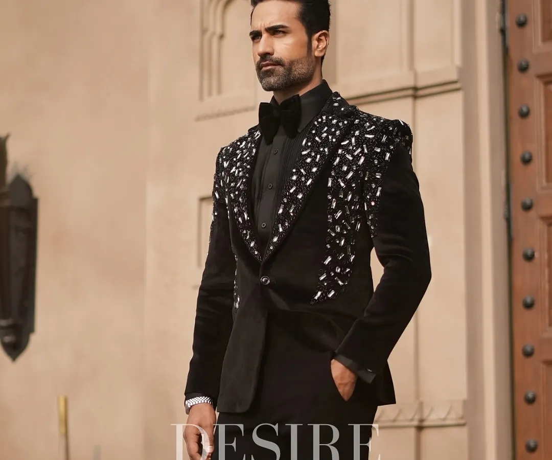 True luxury is in the details. This black velvet tuxedo features a cascade of hand-sewn silver and crystal embellishments on the lapels and shoulders, crafted for the man who appreciates timeless elegance with a modern edge.