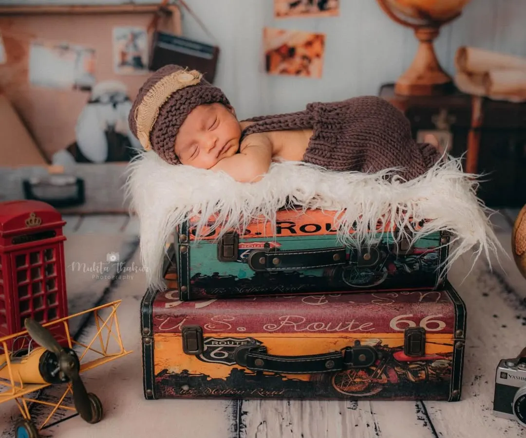 This shot shows a full creative setup for a newborn session. With a 'little traveler' theme, I used vintage suitcases, maps, and a tiny knitted outfit to create a unique and dreamy portrait for this 11-day-old baby boy.