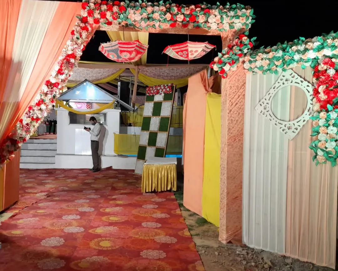 Your guests' first impression matters. We design beautiful and welcoming entrances, like this one featuring a colorful floral arch, traditional decorative umbrellas, and flowing drapes to set a festive tone for the wedding celebration.