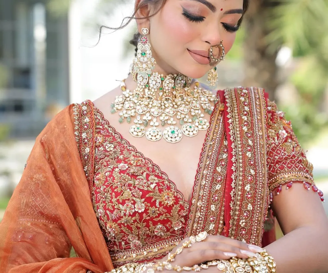 It's all in the details. This close-up showcases a stunning bridal jewelry set with Kundan-style work and delicate emerald green accents. We help you find the perfect rental jewelry, including the nath and maang tikka, to complete your look.