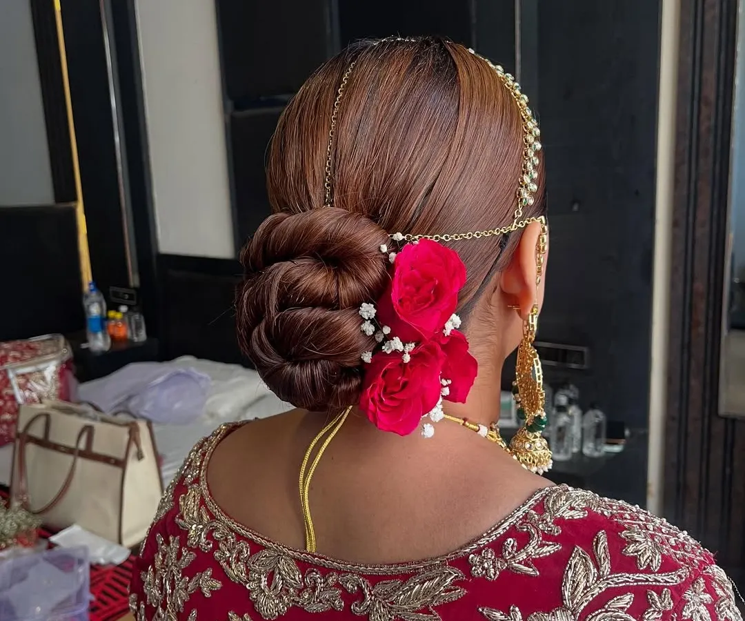 I love creating classic bridal buns that are both secure and beautiful. This intricate twisted updo is accented with vibrant red roses and delicate baby's breath, making it a timeless choice for the main wedding ceremony.