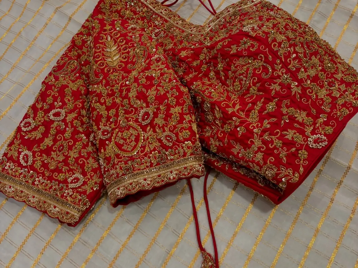 A classic red bridal blouse is timeless for a reason. This piece is covered in heavy, intricate zardosi and thread work, designed to be the perfect regal complement to a wedding saree.