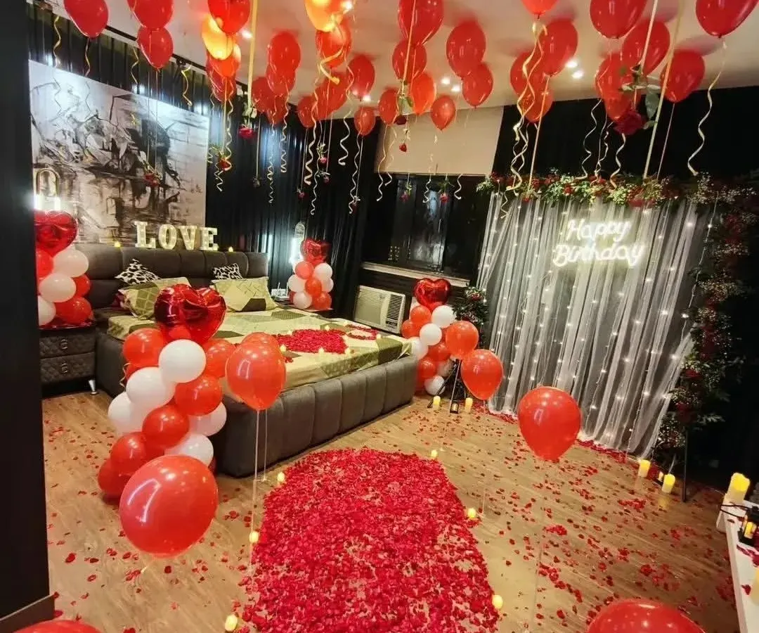 We transform any room into a romantic paradise. This birthday surprise features a dramatic rose petal walkway, hundreds of red and white balloons, and a glowing neon sign, creating an unforgettable grand gesture.