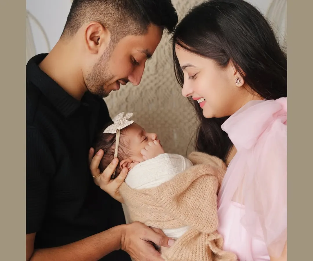 The first family portrait is a memory to hold onto forever. Here, new parents gaze lovingly at their swaddled baby, capturing that initial bond in a simple, beautiful setting.