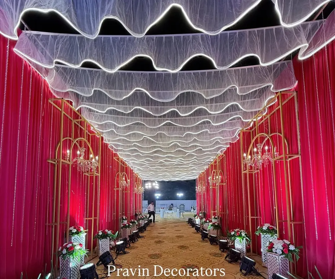 I believe the guest's experience begins at the entrance. Here, we created a dramatic entrance tunnel with flowing red drapes, illuminated white fabric on the ceiling, and elegant chandeliers to build excitement from the very first step.