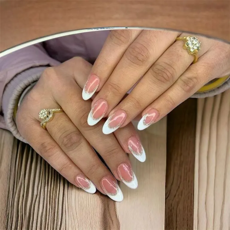 A perfect example of a modern French manicure. I created this elegant look with crisp white tips on an almond-shaped nail, enhanced with a delicate line of silver glitter for a touch of sparkle.