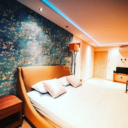 This bedroom features a stunning accent wall behind the headboard with a delicate, floral painted finish. The textured teal and gold design provides a touch of luxury and creates a serene, artistic atmosphere.
