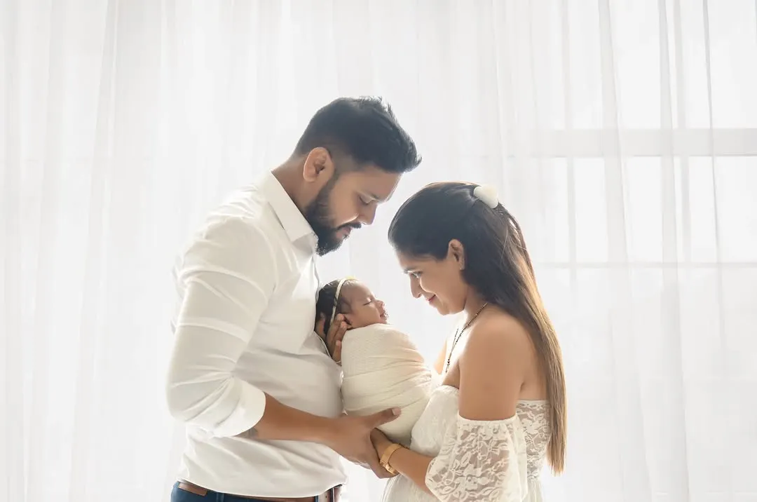 A beautiful, light-filled portrait of new parents adoring their swaddled baby. Capturing this profound connection is a key part of my newborn family photoshoots, creating a memory you will treasure forever.