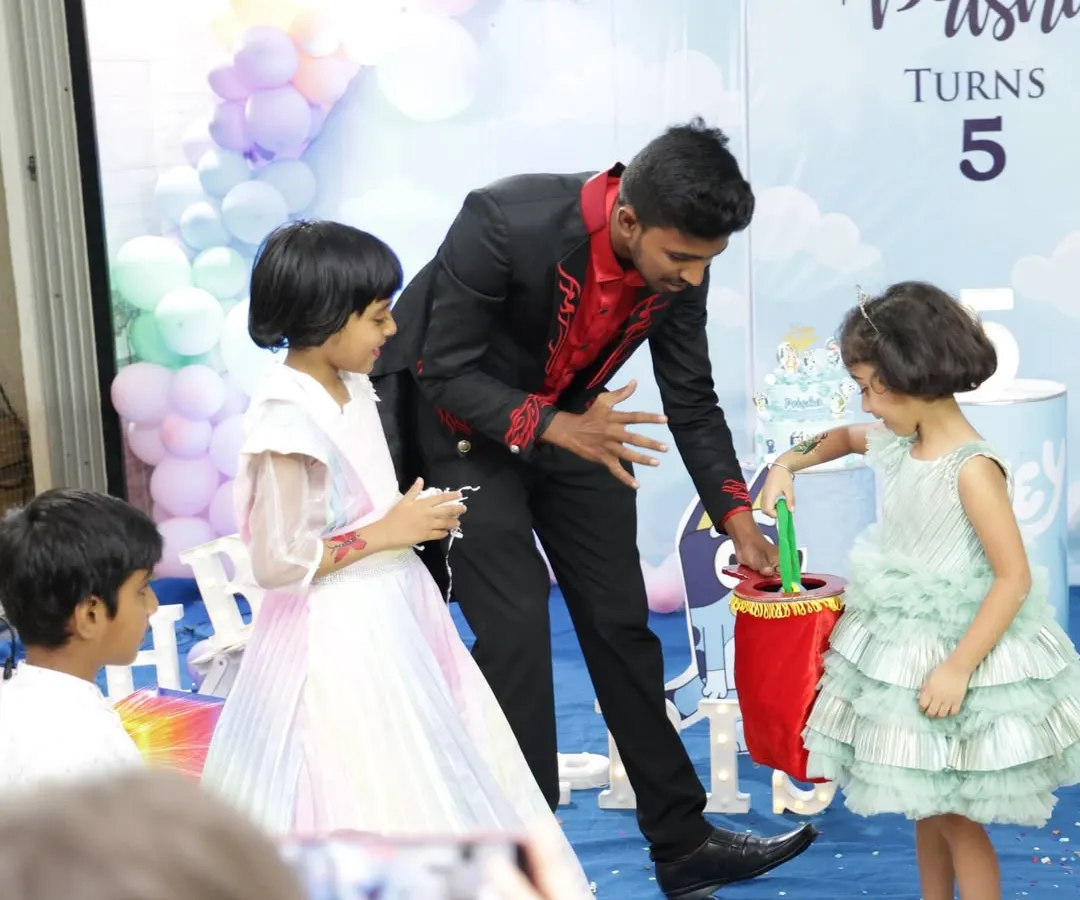 I make sure the kids are the stars of the show. Here, I'm getting some help from two young audience members for a classic "magic bag" illusion at a 5th birthday party. It's all about participation and laughter.