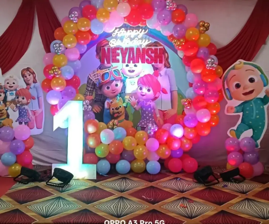 A vibrant and colorful Cocomelon theme for a first birthday party. This setup includes a full balloon arch, character cutouts, and a light-up number '1' to make your child's milestone celebration extra special and fun.